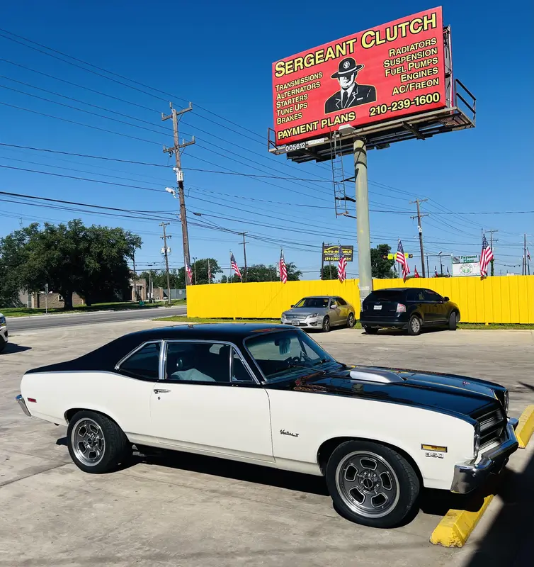Classic Chevelle parked under the Sergeant Clutch billboard