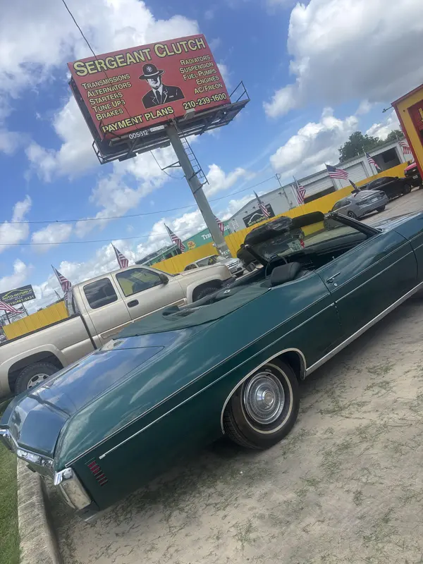 Classic convertible under the Sergeant Clutch billboard